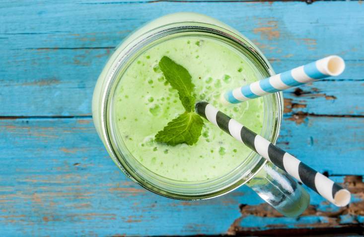 Refreshing Summer green smoothie or milkshake with mint, yogurt and kiwi. in mason jar, on blue wooden table, copy space, top view