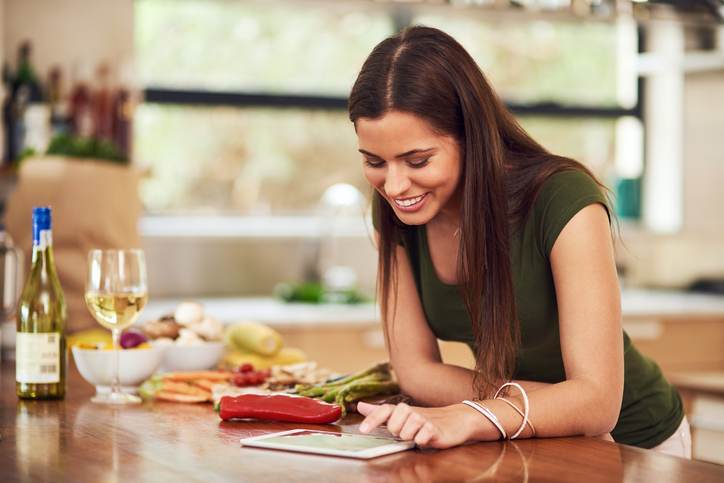 Shot of an attractive young woman using her tablet to look up a recipe in her kitchen