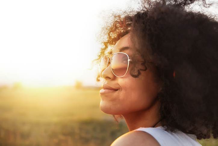 Portrait of african woman enjoying the sun, waling on road.