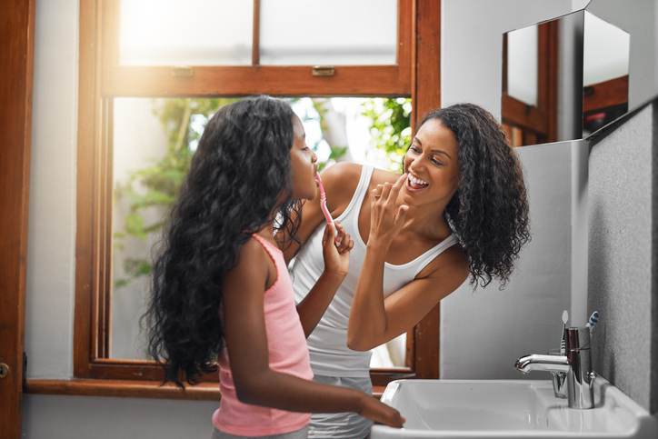 Cropped shot of an attractive young woman and her daughter brushing their teeth in the bathroom at home