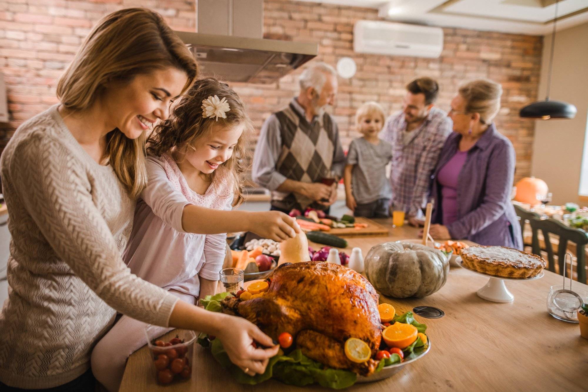 Happy mother and daughter preparing roasted turkey for Thanksgiving dinner. Discover Thanksgiving 2022 Shopping in Garland at Northstar Plaza